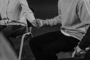 Close-up of people holding hands in a peer-led support group.