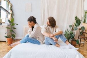 A distressed woman sits beside her partner, depicting the emotional strain that unresolved childhood trauma can have on adult intimacy.