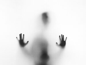 A shadowy figure pressing their hands against the glass