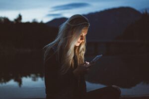 A woman looking at her phone in the dark before getting sex addiction treatment in Idaho
