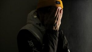 A man with a yellow beanie pulled down over his face, emphasizing anonymity and a casual style.