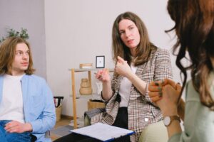 A woman converses with a man and a woman, all appearing engaged and attentive.