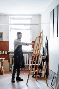 A man in a therapy room painting on canvas