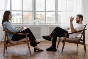 An image of a man and woman talking while sitting on chairs opposite each other