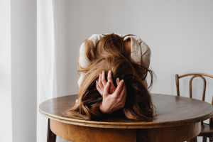 Frustrated woman lying face-down on a table, symbolizing the emotional burden of hidden porn addiction in women.