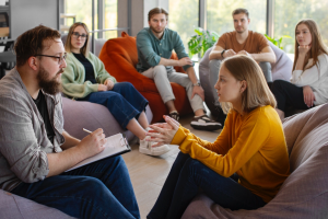 Group of people seated in a circle during a therapy session.