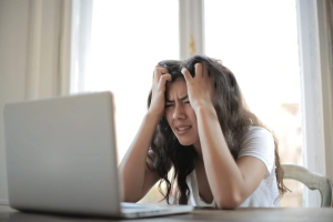 Woman sitting at a desk with a laptop, symbolizing mindful and lawful online engagement during recovery.