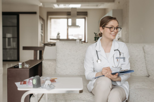 An image of a woman wearing a white coat and sitting on a couch