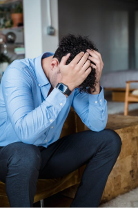 An image of a man sitting with his head in his hands