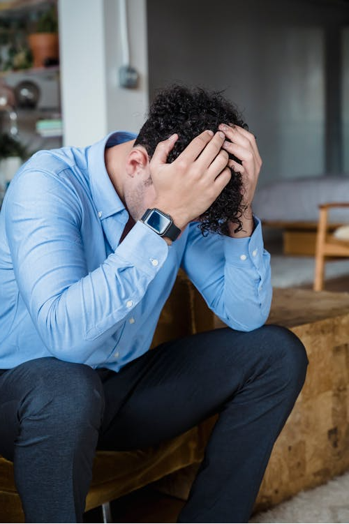 An image of a man sitting with his head in his hands