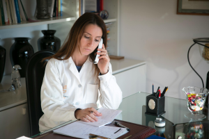 An image of a woman in a white coat talking on the phone
