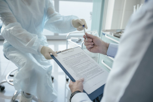An image of a person handing a paper and pen to another person