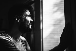 Greyscale image of a man looking through a window.
