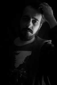 Man wearing a black-and-white crew-neck shirt standing indoors.