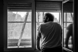 Man standing beside a window indoors.