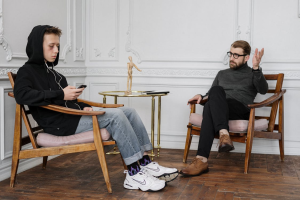 Man sitting in therapy session with a counselor, discussing recovery strategies for sexual addiction.