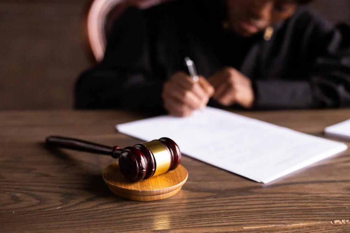 A gavel resting on a desk while paperwork is completed.