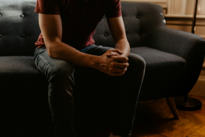 A man sitting on a sofa with his hands folded