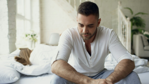 A man sitting sadly on a bed